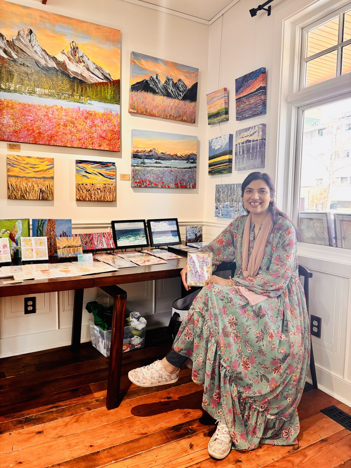 Afshan Khan seated beside her original paintings